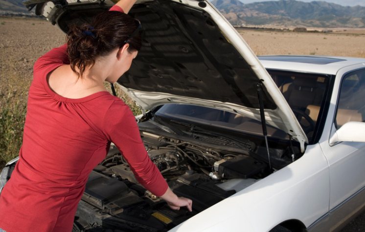 Woman checking under the hood of a car